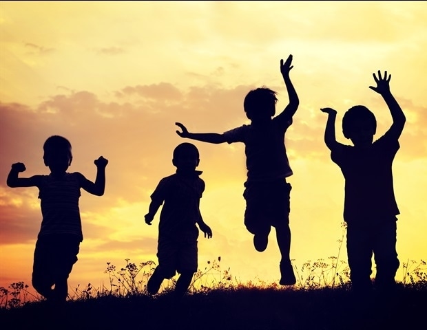 Four children jumping with a sunset behind