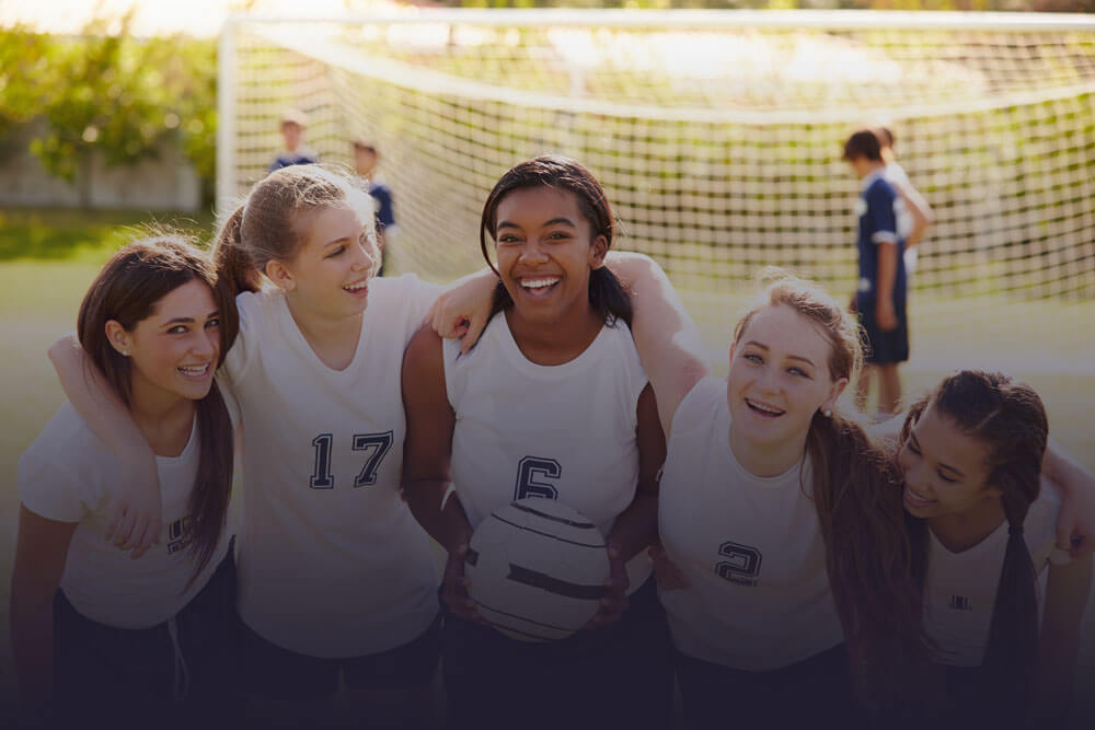 A group of girls posing with a soccer ball.