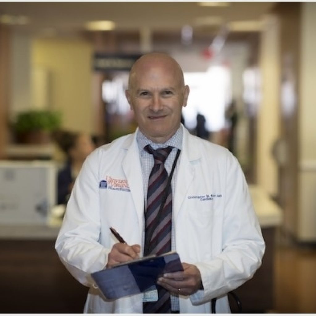 A doctor standing writing on a report